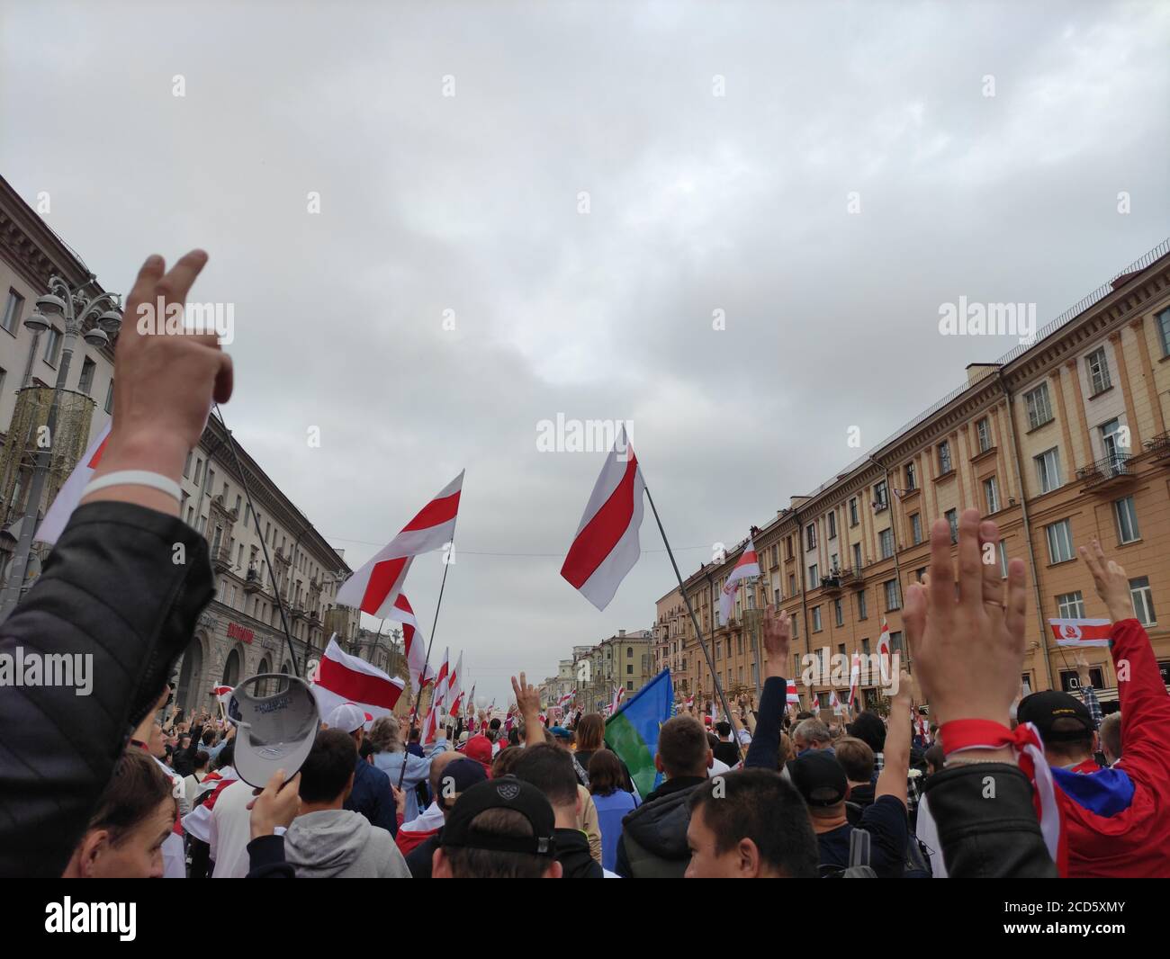 Minsk / Belarus - August 23 2020: Protesters with white-red-white flags raising hand in the victory sign while marching  through the city center Stock Photo