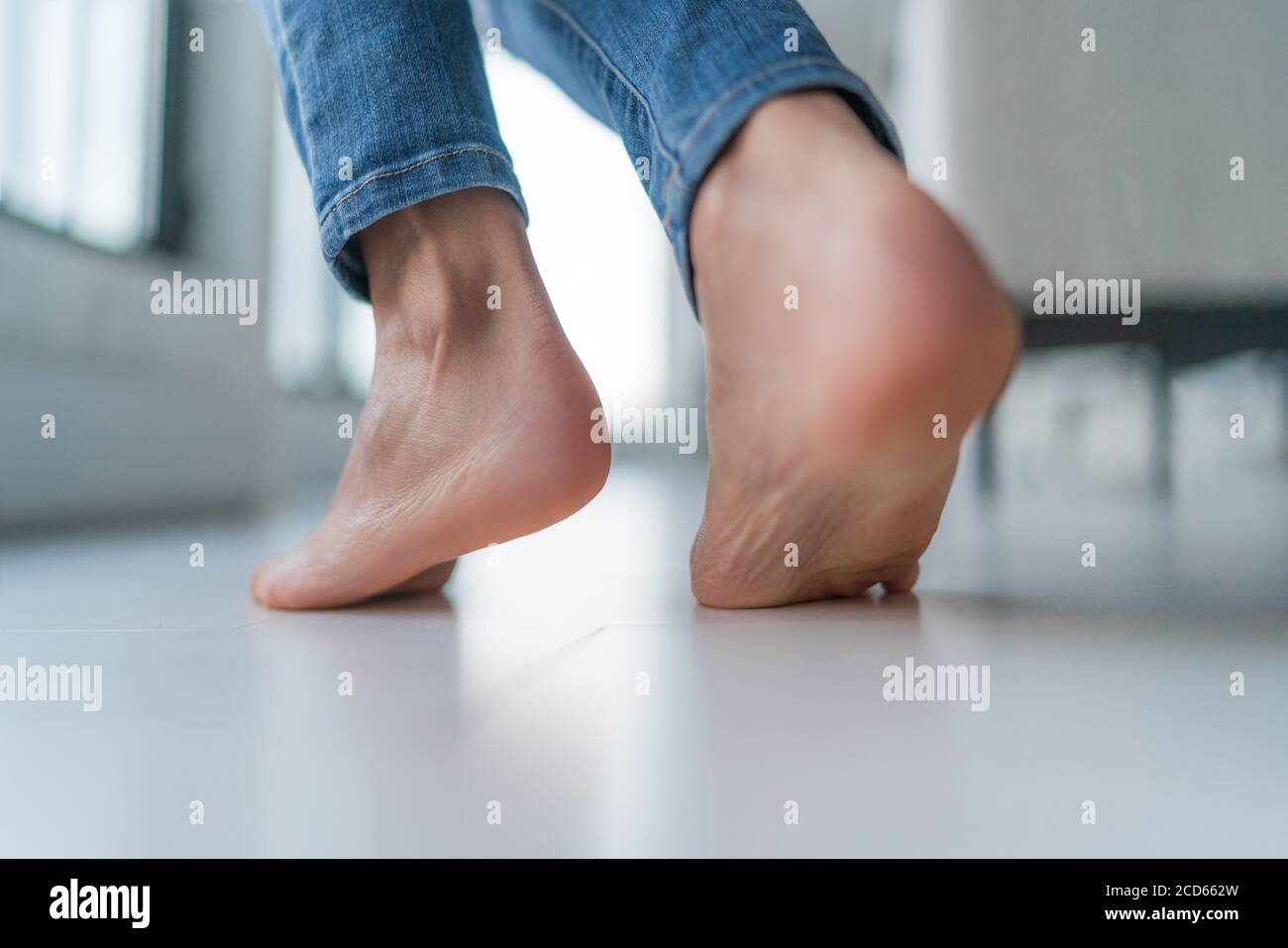 Floor heating woman walking barefoot on hardwood floor in winter inside home. Comfort living room lifestyle. Closeup of women feet Stock Photo