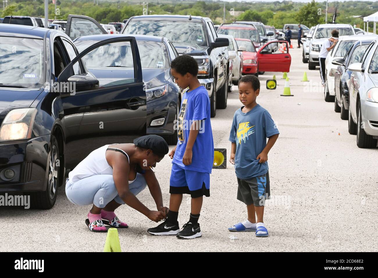 Austin, TX USA August 26, 2020: Hundreds of cars from coastal east Texas and southwest Louisiana wait in line at a Hurricane Laura evacuation center at the Circuit of the Americas race track. After spending hours in their family car, this woman and kids finally get some fresh air. Early-arriving drivers received vouchers for hotel rooms. Once those ran out, drivers were directed to other evacuation centers in Waco and Dallas. Laura is expected to make landfall overnight as a Category 4 storm and wreak havoc along the Texas and Louisiana coasts and inland. Credit: Bob Daemmrich/Ala Stock Photo