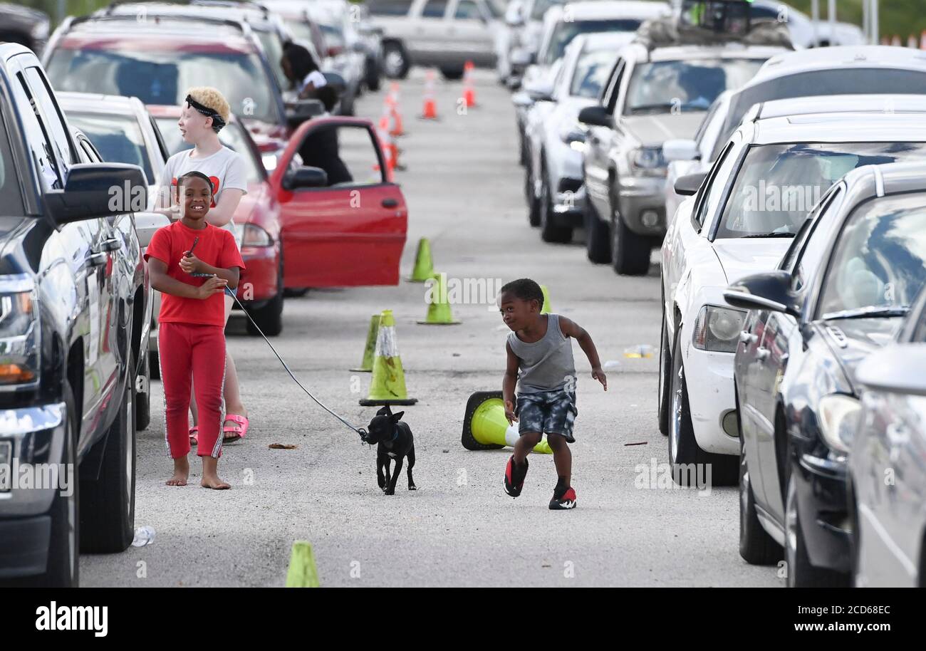 Austin, TX USA August 26, 2020: Hundreds of cars from coastal east Texas and southwest Louisiana wait in line at a Hurricane Laura evacuation center set up by Austin officials at the Circuit of the Americas race track parking areas. Early-arriving drivers received vouchers for hotel rooms. After spending hours in their family car, these kids stretch their legs while walking their dog. Laura is expected to make landfall overnight as a Category 4 storm and wreak havoc along the Texas and Louisiana coasts and inland. Credit: Bob Daemmrich/Alamy Live News Stock Photo