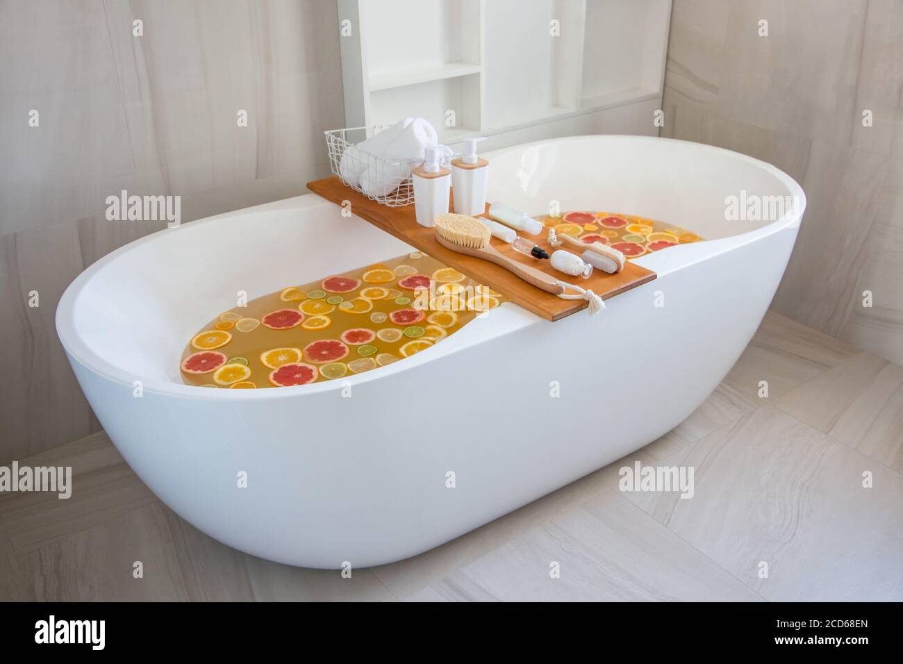 Bathtub filling with water, mixed slices of fresh citrus fruits and spa