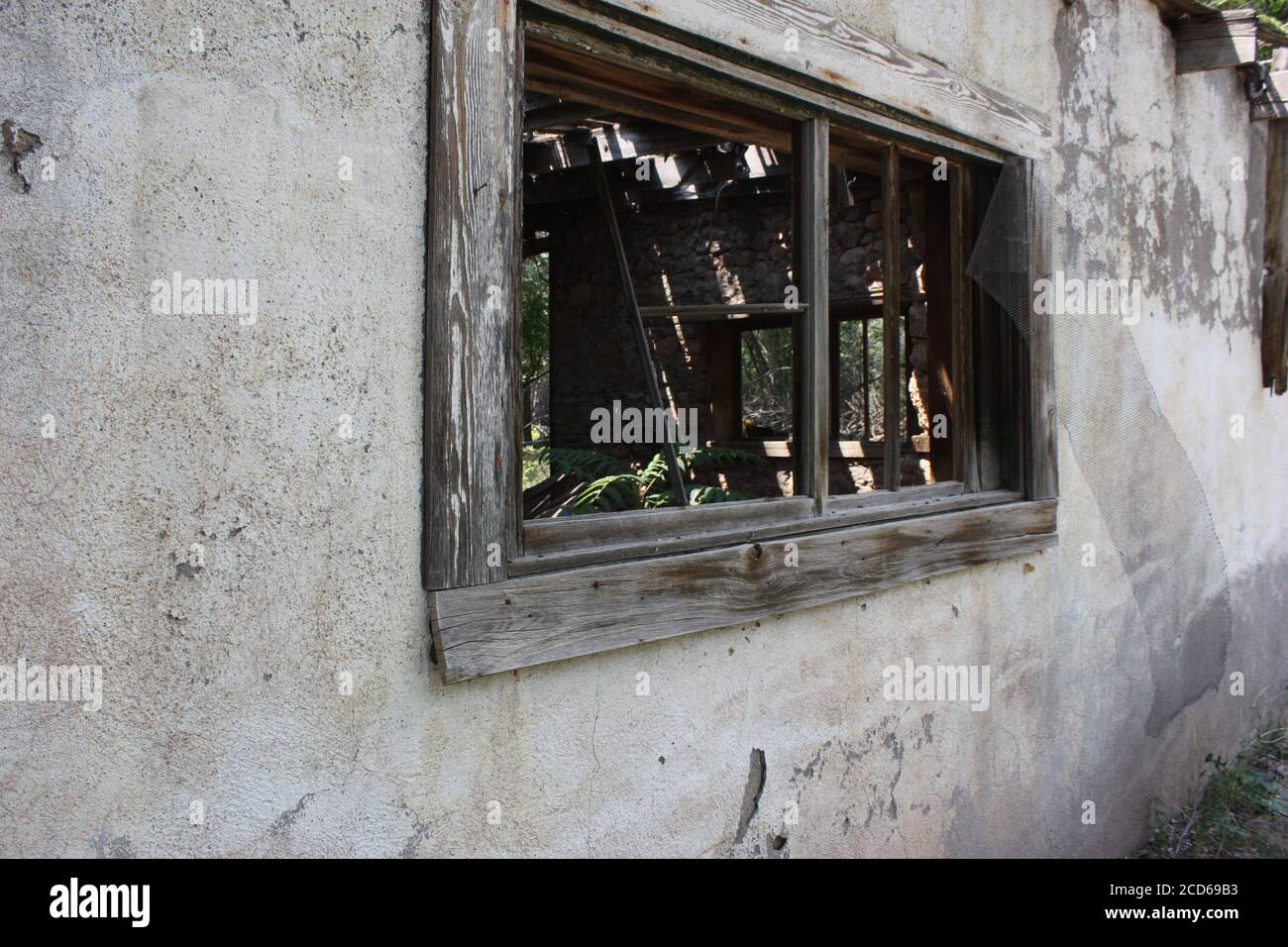 Eerie worn, wood windows of an abandoned old adobe building in a ghost town. Stock Photo