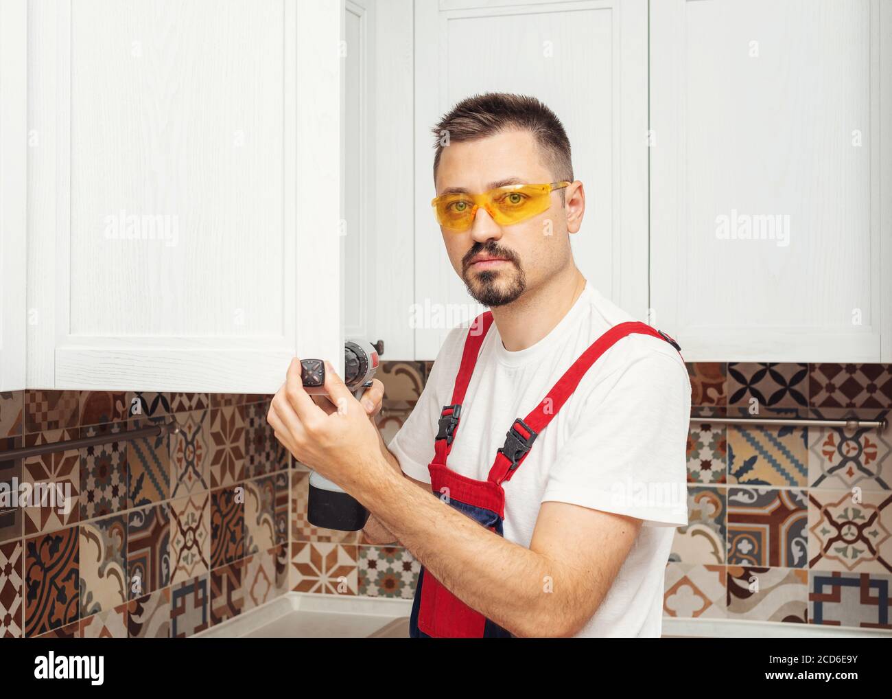 Maintenance worker installing new furniture with screwdriver and look at camera Stock Photo