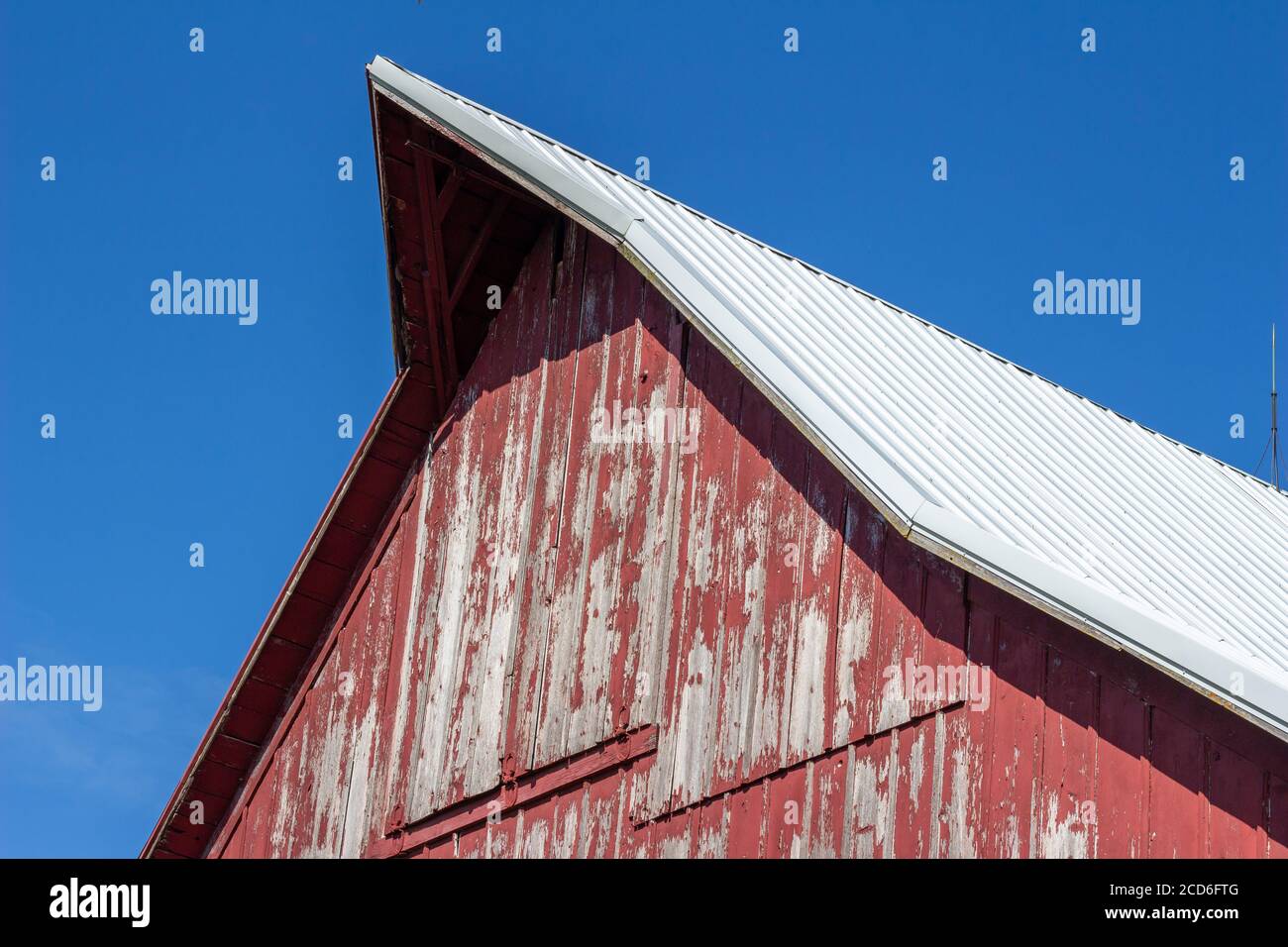 Close upward view of a hayloft door on a rustic late 19th Century wooden barn with blue sky and copy space Stock Photo