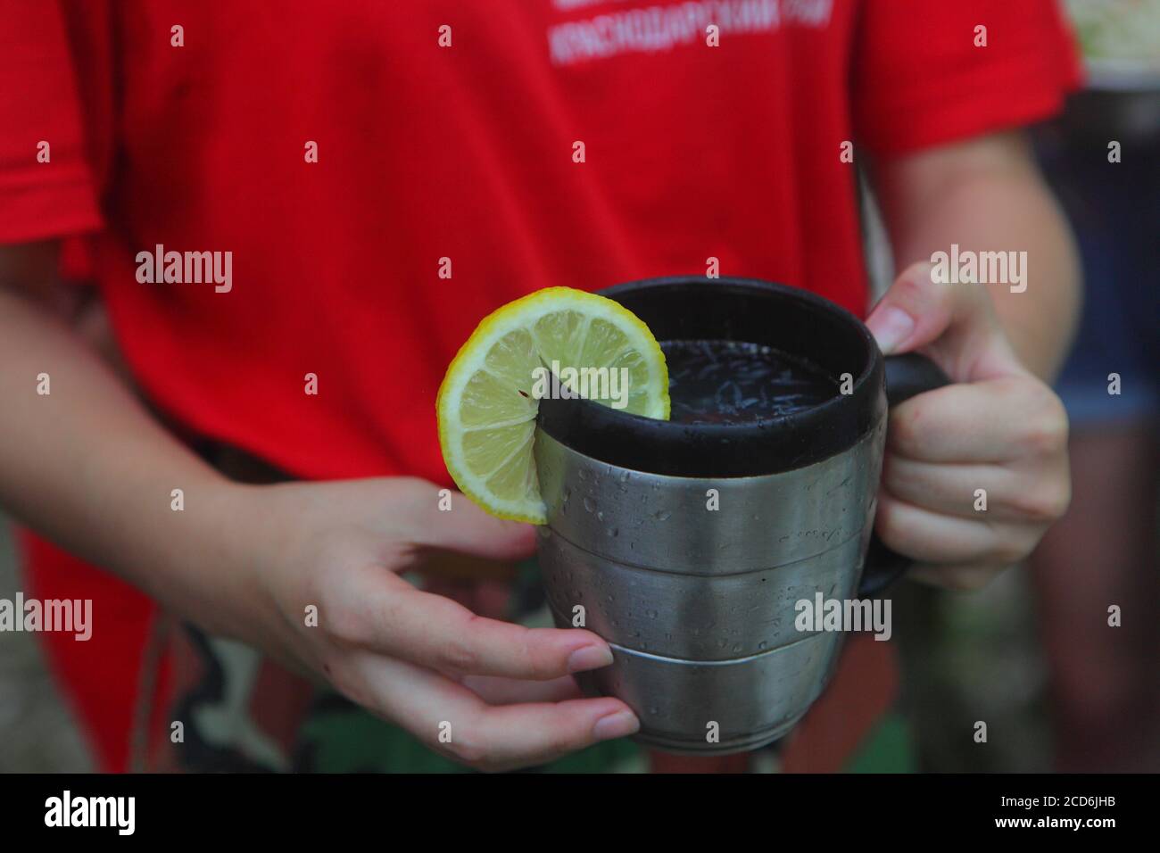 Children's hands hold a red mug with tea in the autumn park Stock Photo