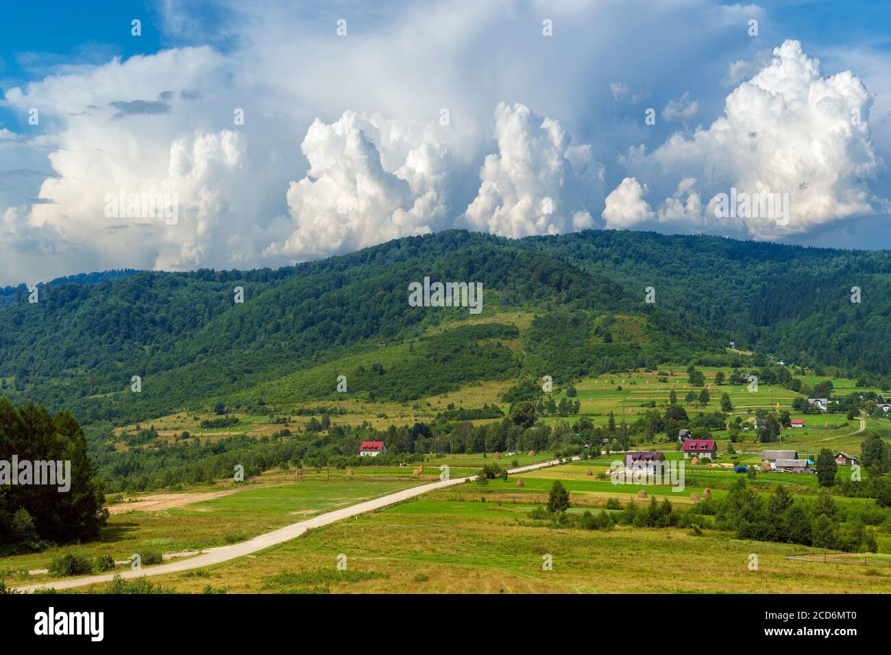 Summer day landscape with road, cloudy sky and small houses Stock Photo ...