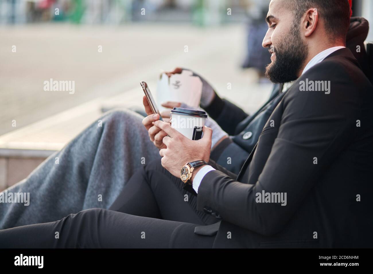 Man in tuxedo, brunette, bearded, with beautiful expensive watches sitting on street Stock Photo