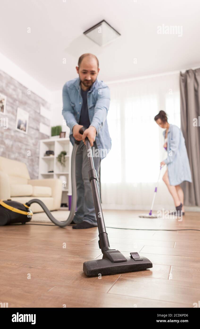 Cleaning floor with vacuum cleaner used by husband Stock Photo Alamy