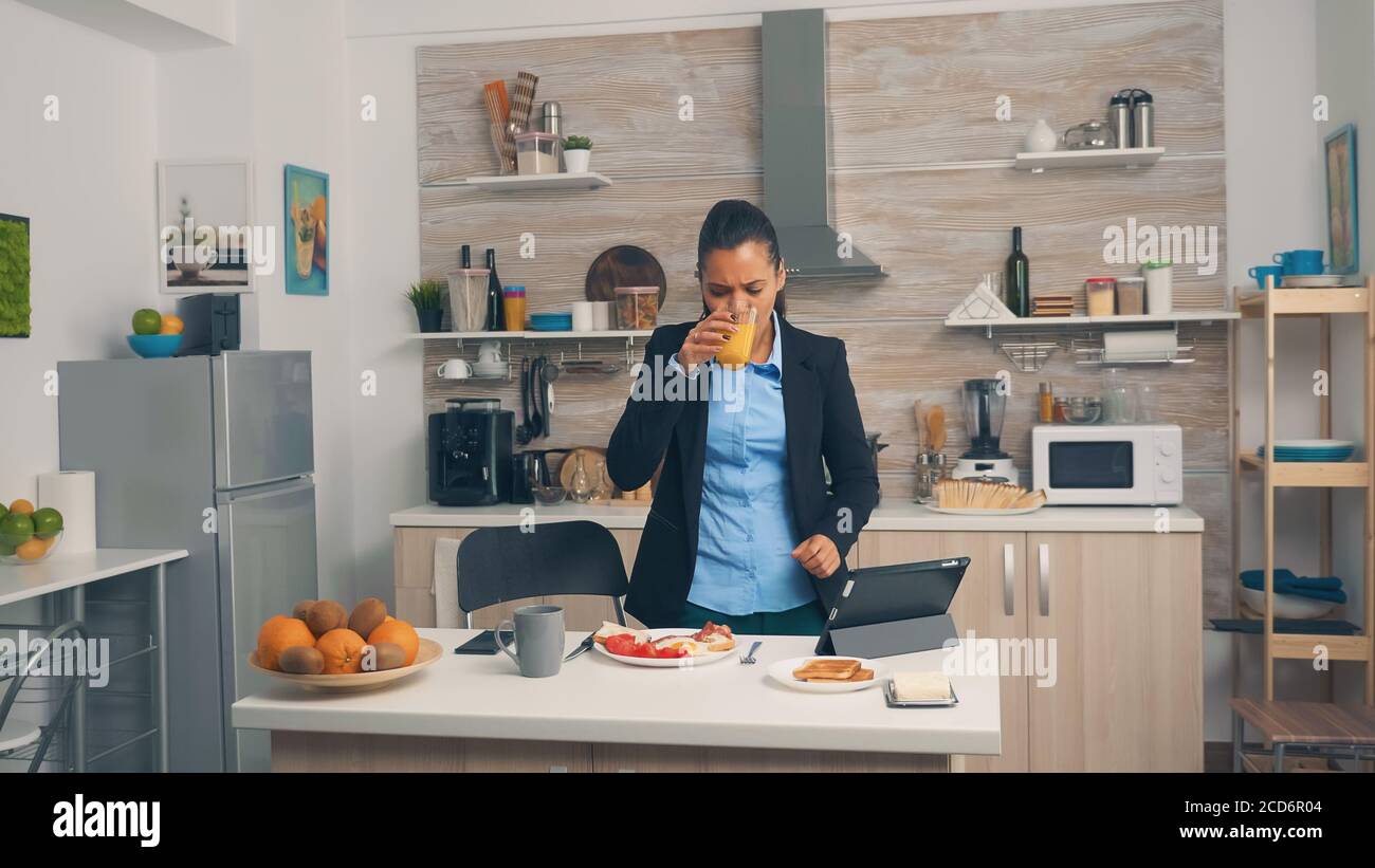 Businesswoman rushing at the office during breakfast. Young freelancer working around the clock to meet her goals, stressful way of life, hurry, late for work, always on the run Stock Photo