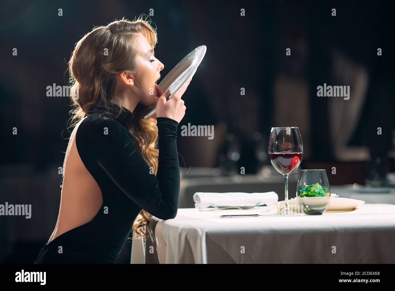 A young woman licks a plate in a restaurant Stock Photo - Alamy