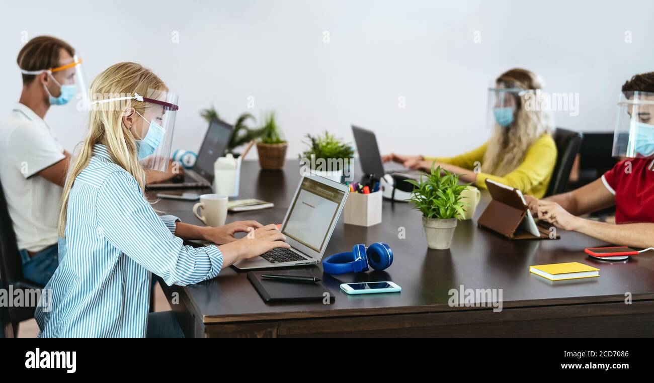Young people in co-working creative space wearing surgical mask protection for preventing corona virus spread Stock Photo
