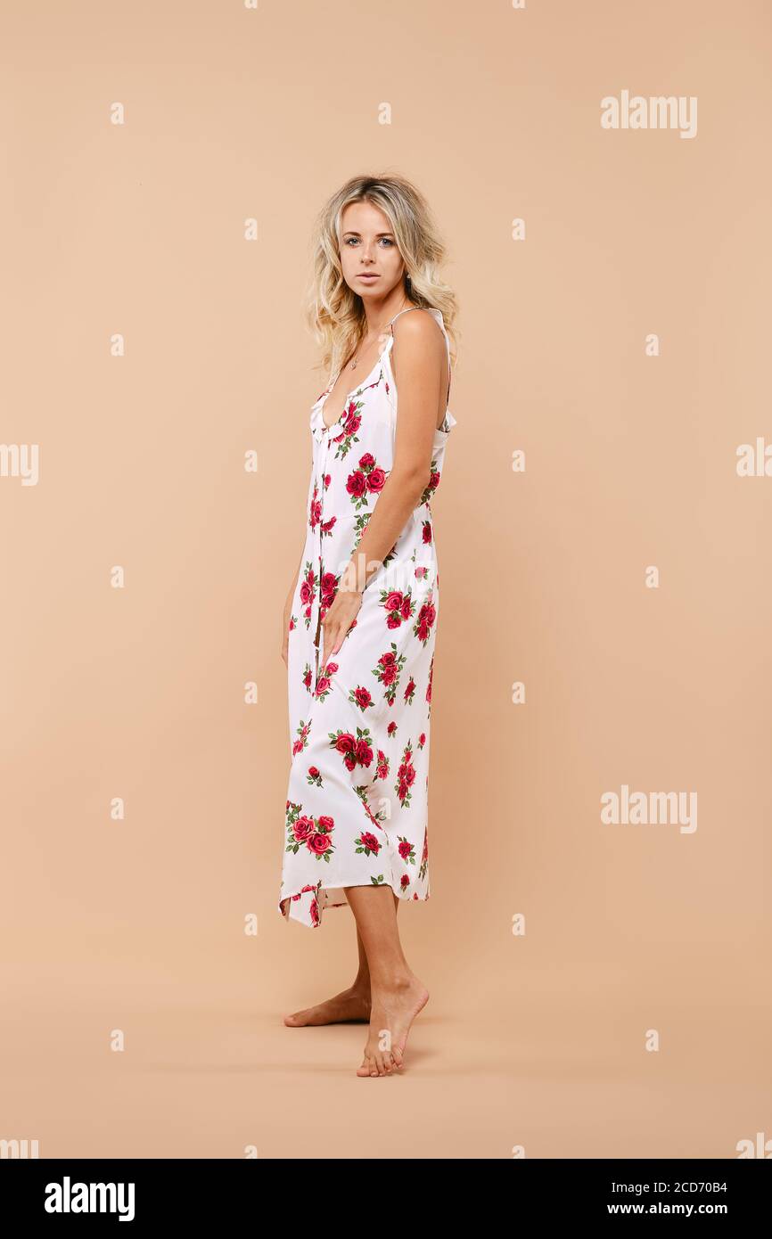 Full length portrait of cute woman in long sundress on straps over beige background Stock Photo