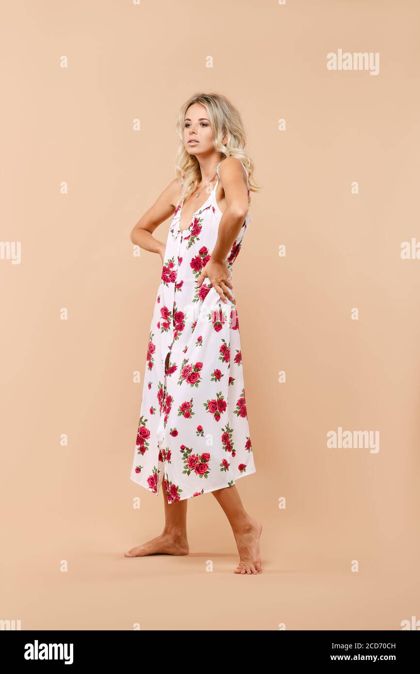 Full length portrait of cute woman in long sundress on straps over beige background Stock Photo