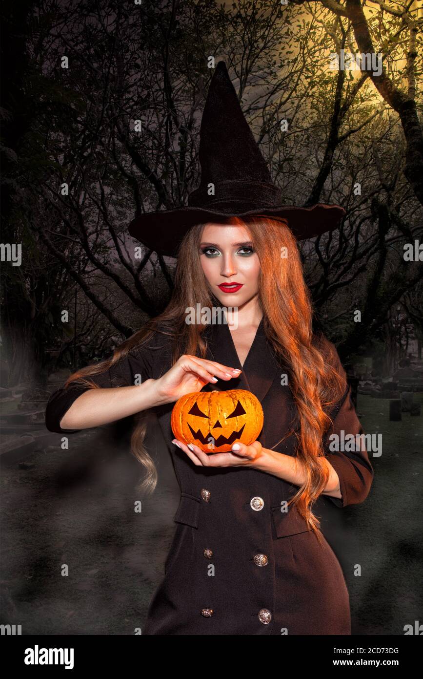 Witch woman in Halloween costume with long curly hair and perfect makeup Stock Photo