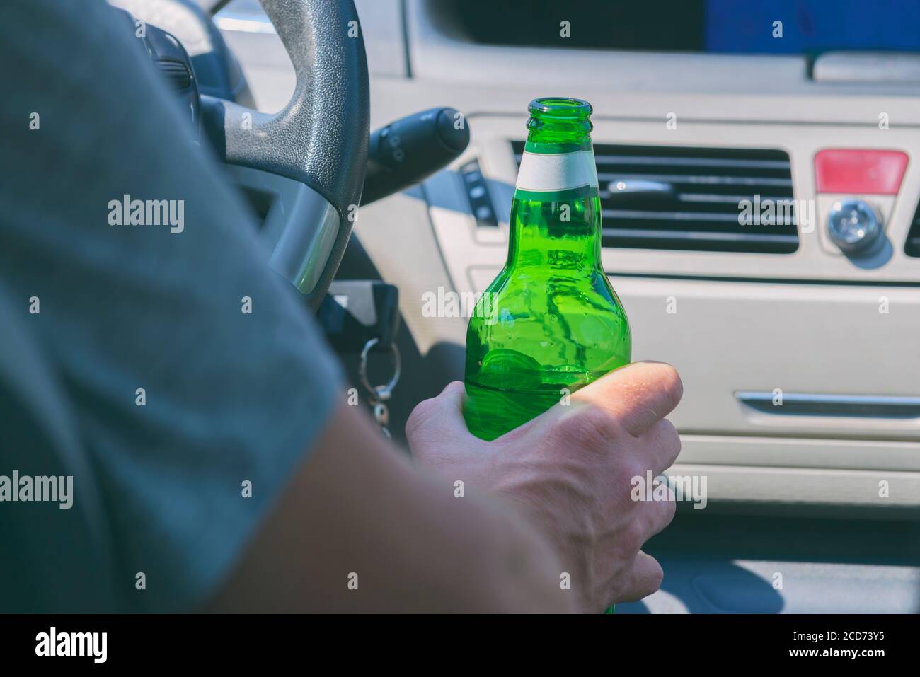 Man holding green bottle of beer in hand while driving a car. Don't ...
