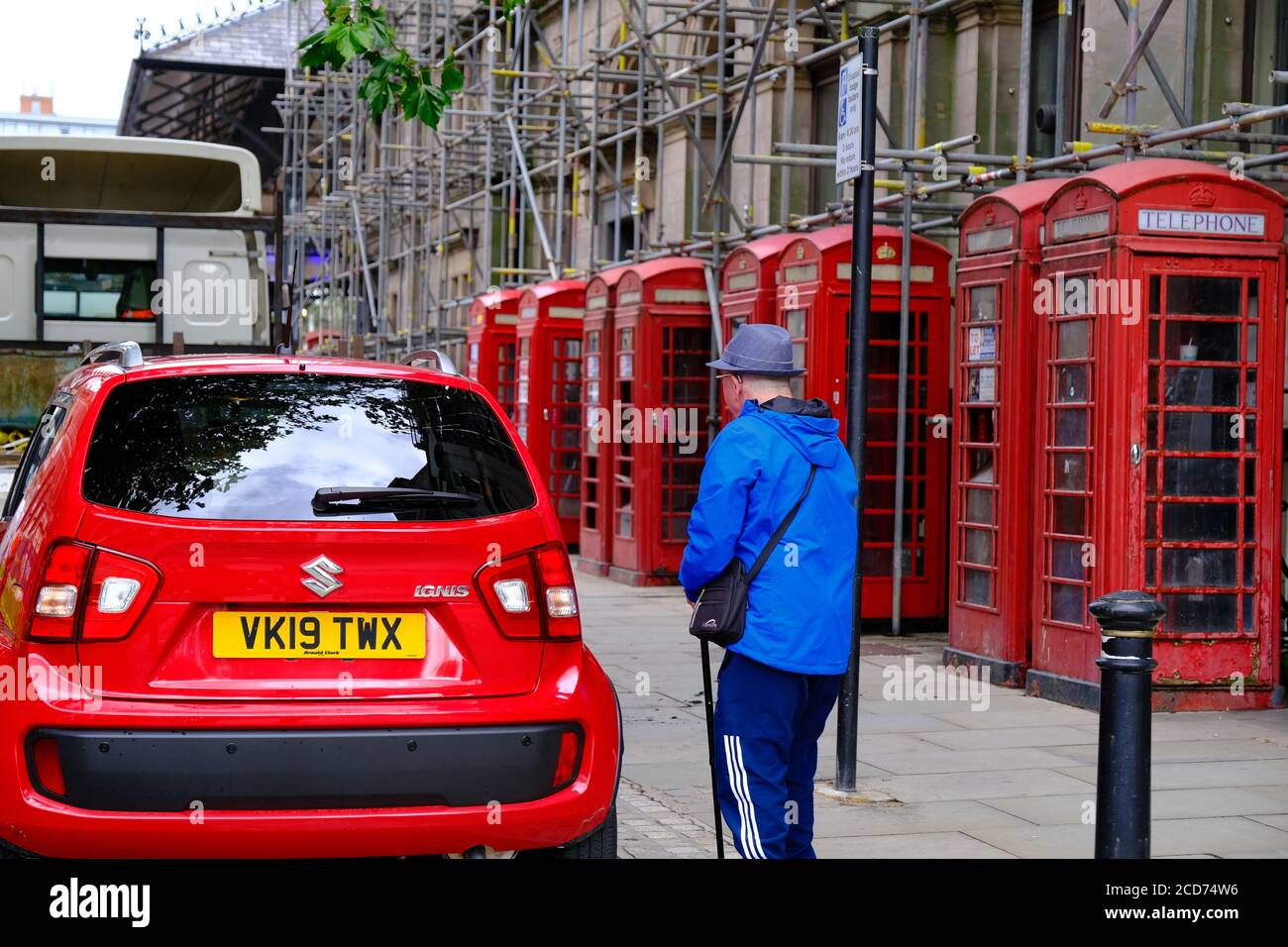 Red car in front of a row of eight traditional red telephone boxes in Presto's city centre. Stock Photo