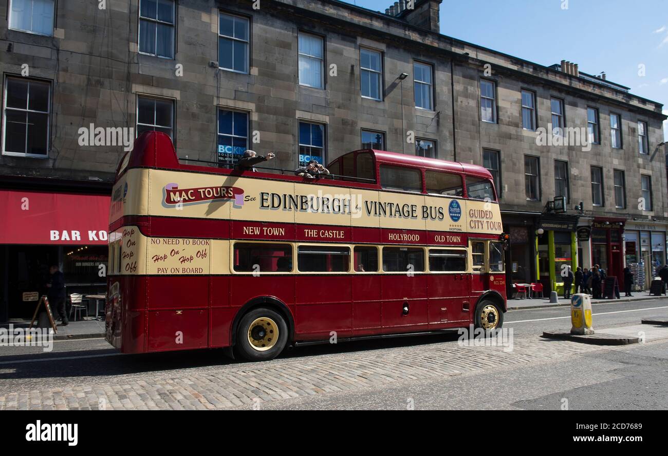Tourists enjoying an open top bus tour of the city of Edinburgh on a vintage double decker bus. Stock Photo