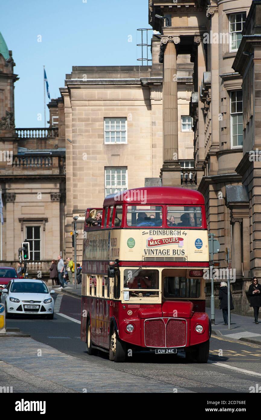 Tourists enjoying an open top bus tour of the city of Edinburgh on a vintage double decker bus. Stock Photo