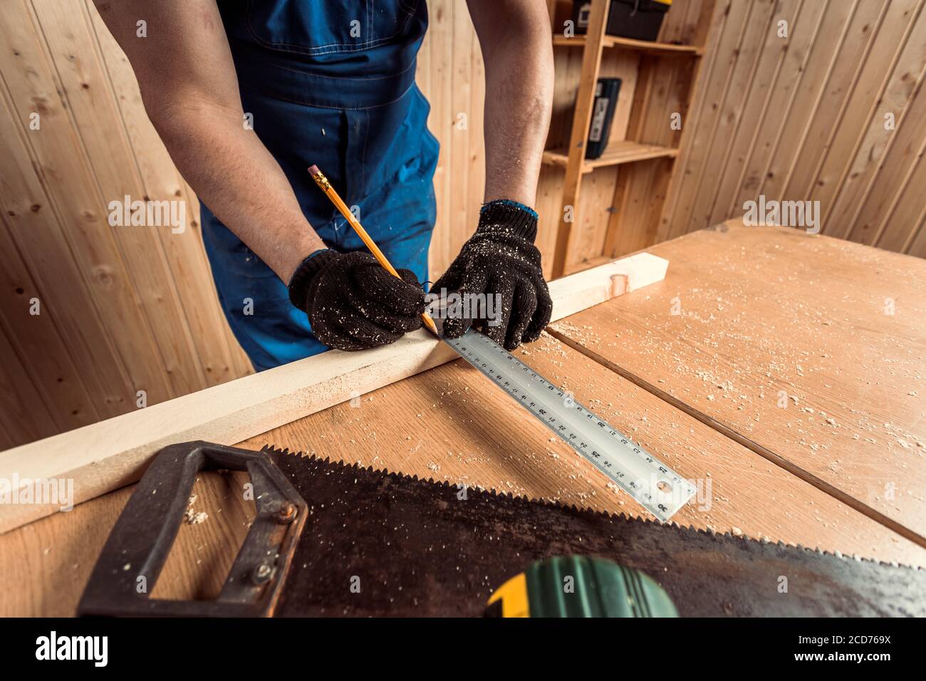 close-up of a male joiner measures with a ruler and a pencil dimensions ...