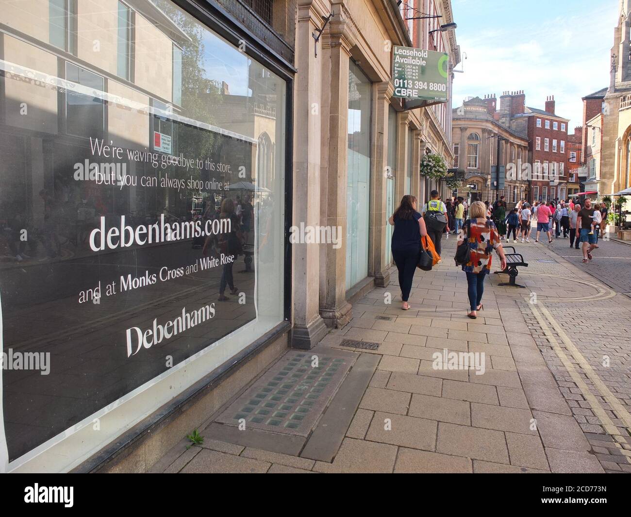Shoppers pass a sign in the window of struggling UK chain department store Debenhams on Davygate in York saying that branch has closed down. Stock Photo