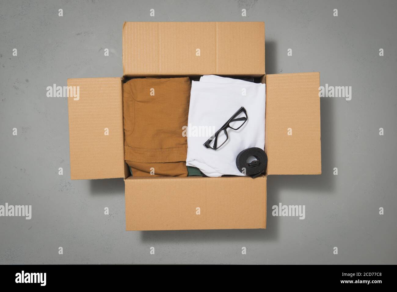 Cardboard donation box with clothes on gray background Stock Photo - Alamy