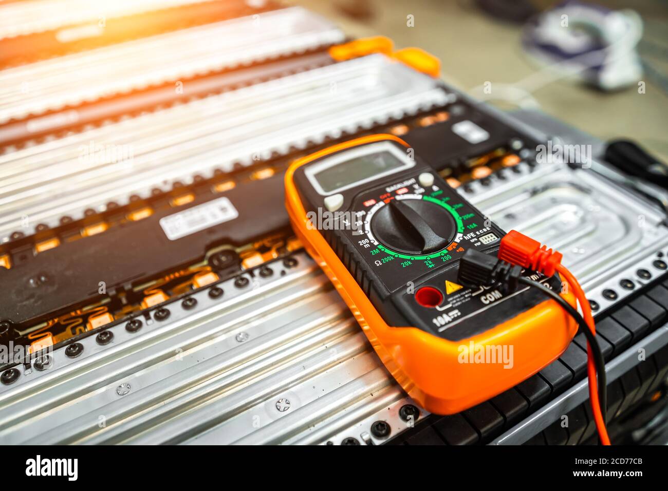 the multimeter is lying on the battery of an electric car on a blurry background. Stock Photo