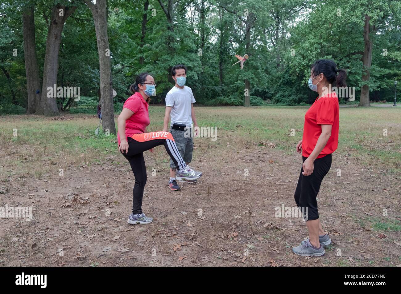 3 Chinese Americans in surgical masks play Jianzi, at a park in Flushing, Queens, New York City. Stock Photo
