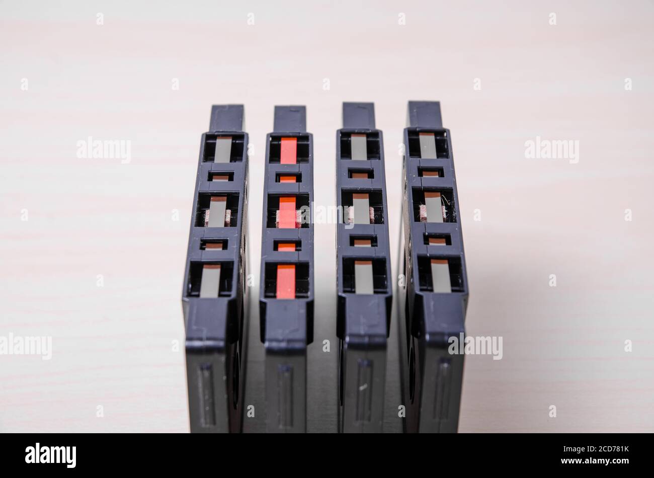 Set of audio cassette tapes with visible tape on wooden desk or table, in line, order