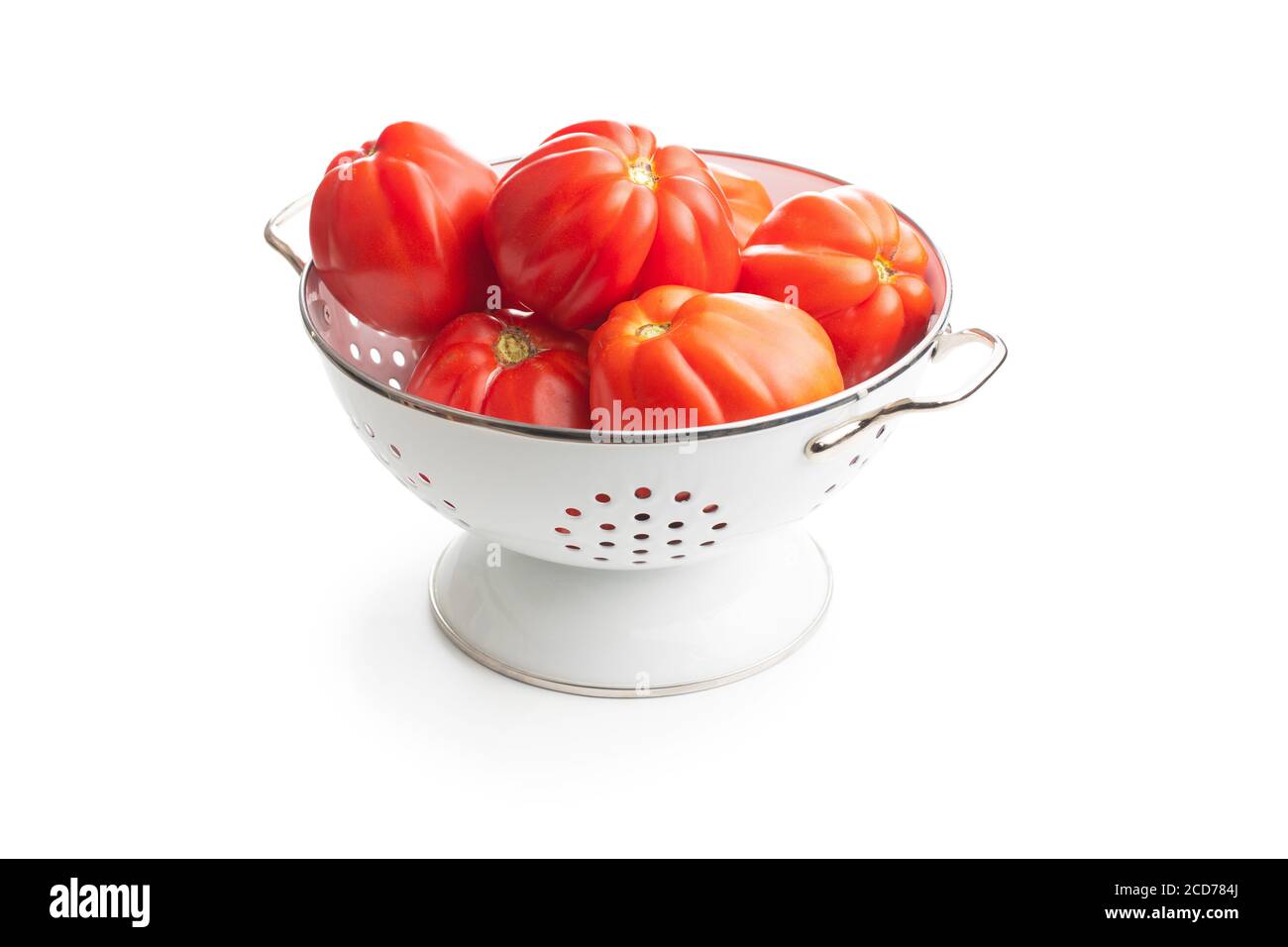 Red beefsteak tomatoes in colander isolated on white backround. Stock Photo