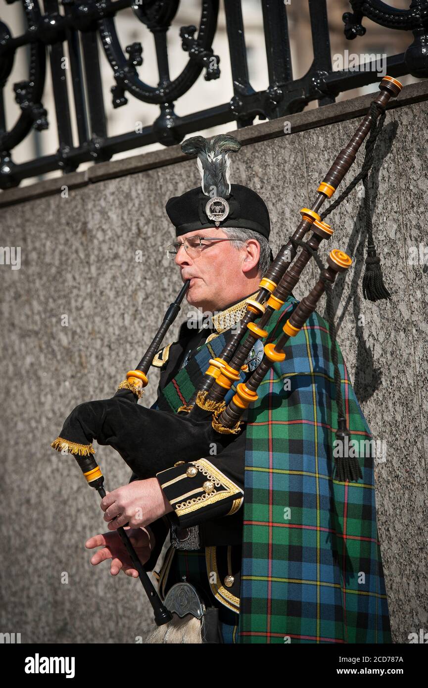 Bagpipe player dressed in traditional scottish tartan playing the