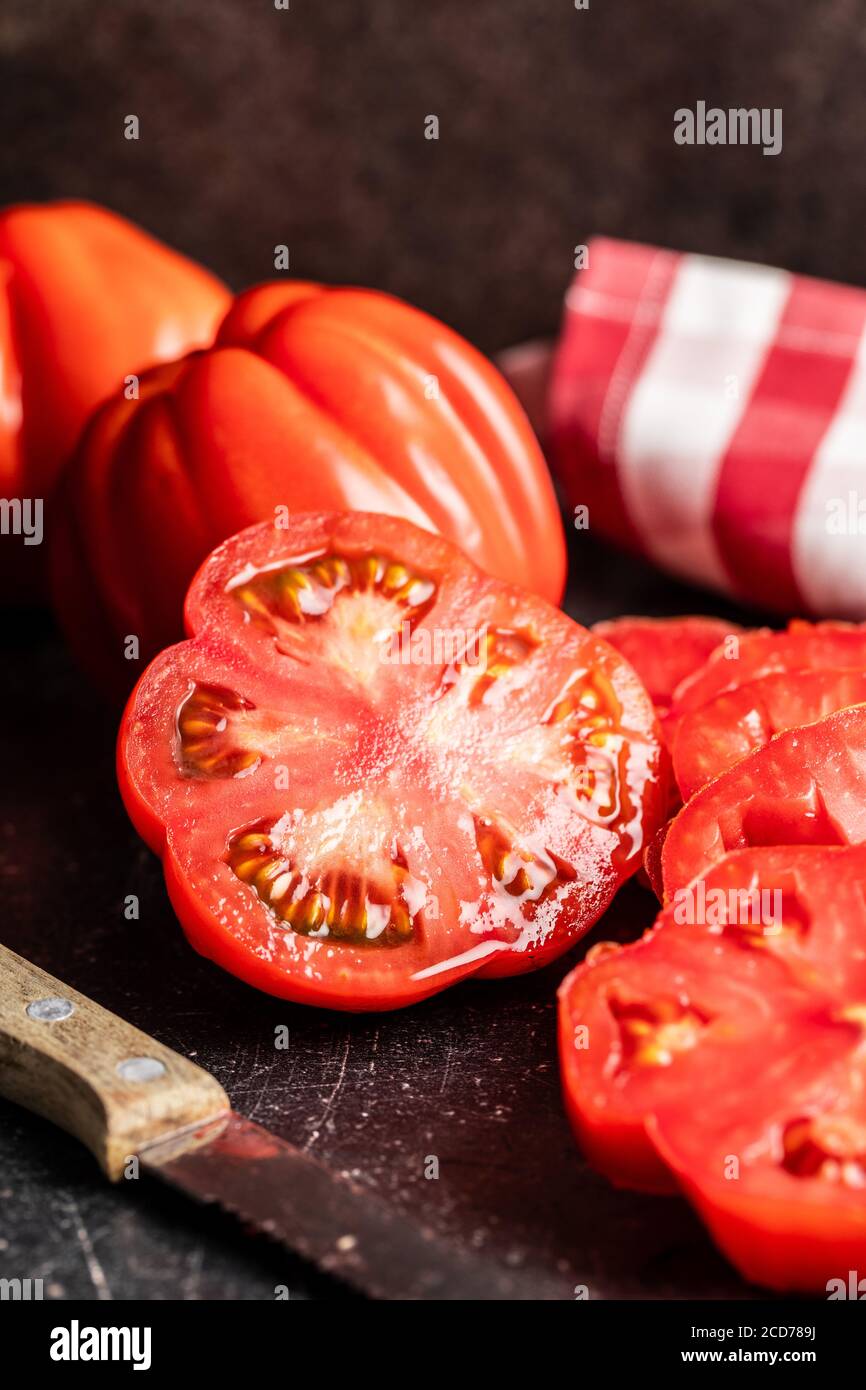 Sliced red beefsteak tomatoe on black table. Stock Photo