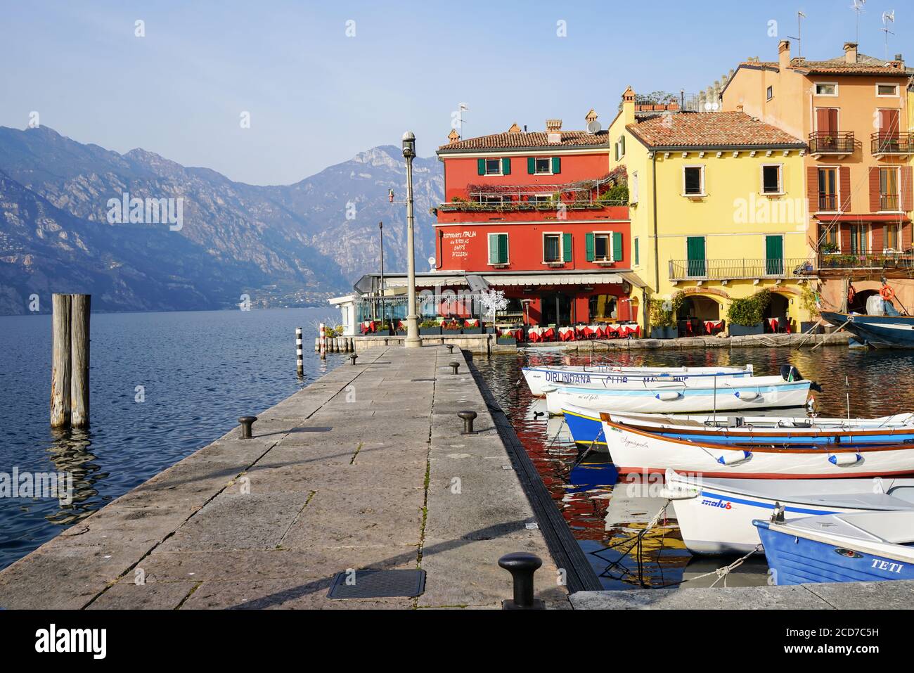 Sunny day in colorful marina of Malcesine with small boats tied up to the pier Stock Photo