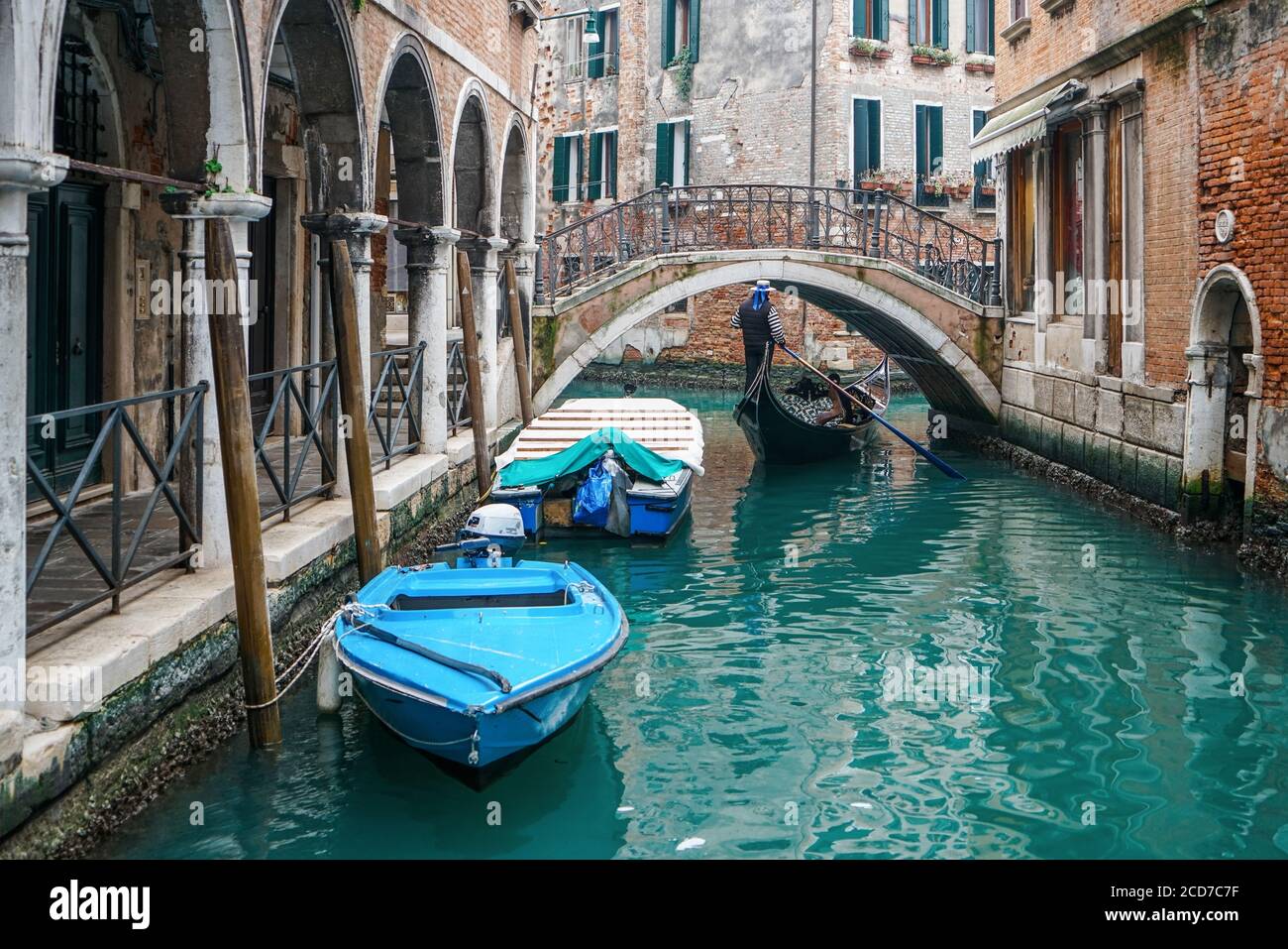 Gondolier riding a gondola under the beautiful Ponte del Piovan bridge in a Venetian water canal. At Venice, Italy Stock Photo