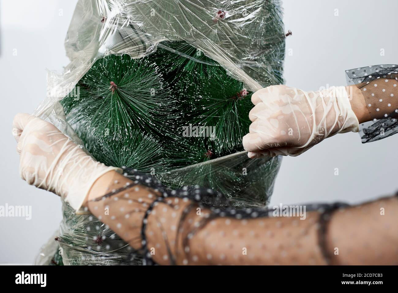 https://c8.alamy.com/comp/2CD7CB3/plastic-wrapped-christmas-tree-woman-in-medical-gloves-cutting-and-tearing-saran-wrap-re-opening-xmas-holidays-after-covid-19-quarantine-2CD7CB3.jpg