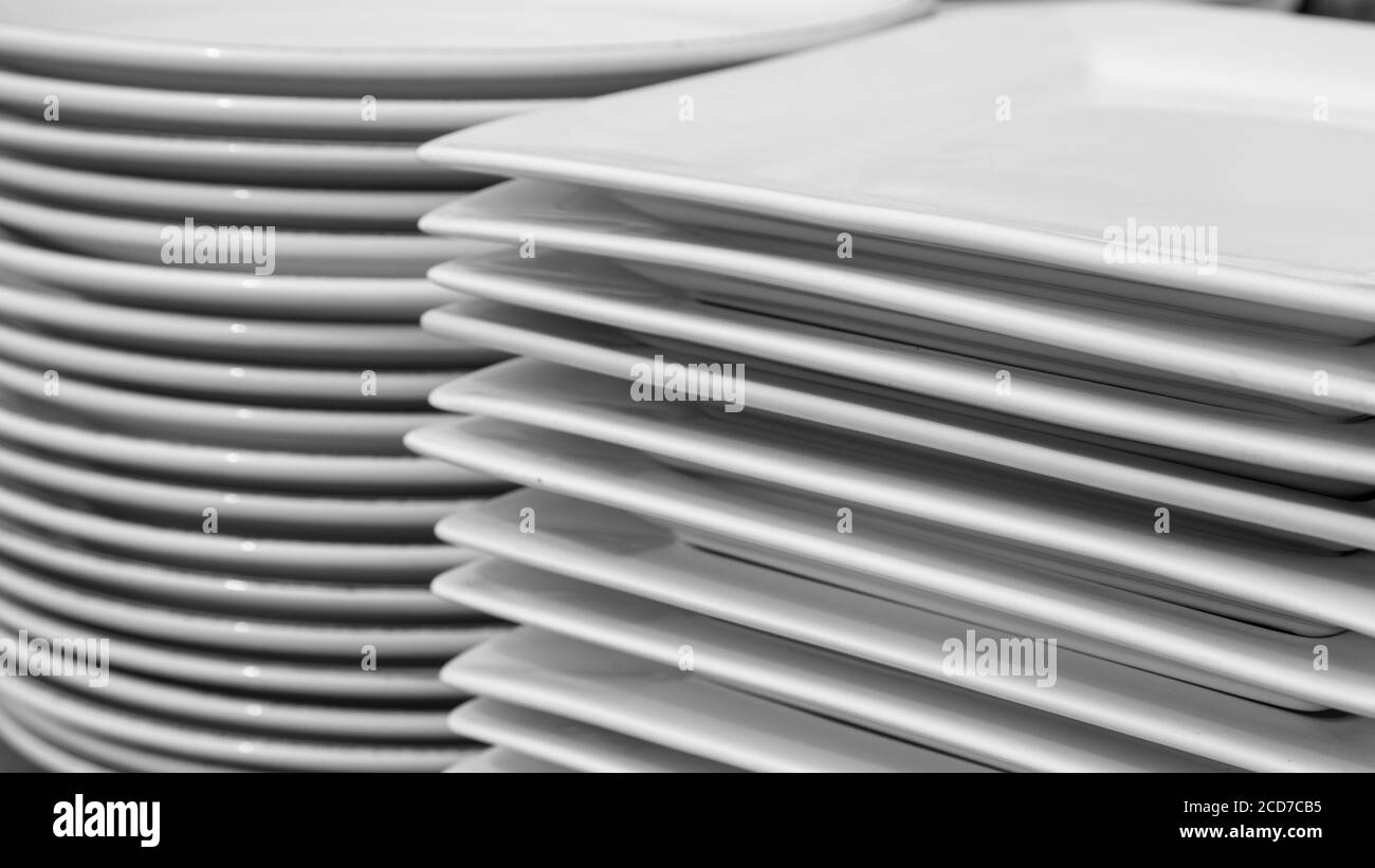 Stack of clean white round and square restaurant dishes. Stock Photo