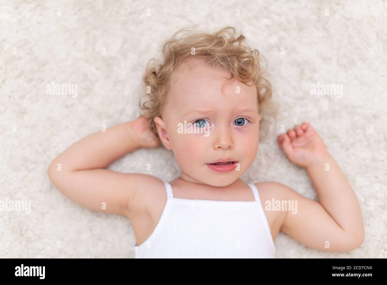 Portrait of a little girl who lies on the carpet Stock Photo - Alamy