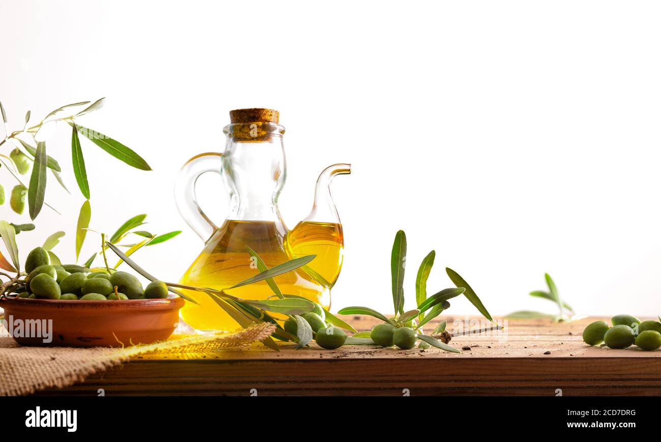 Olive oil on wooden table with raw olives and leaves with isolated