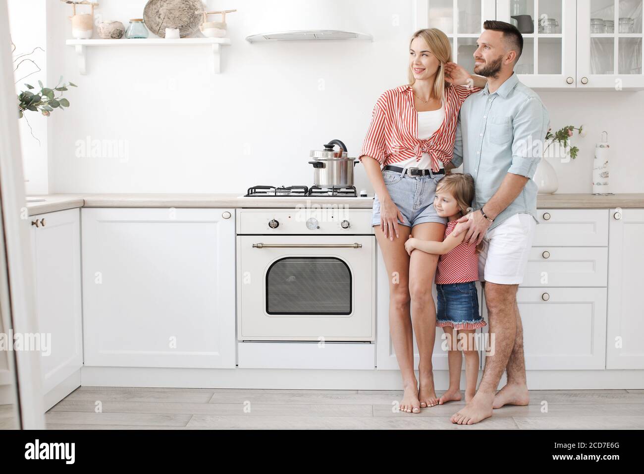 Happy family with daughter in casual wear at home in kitchen  Stock Photo