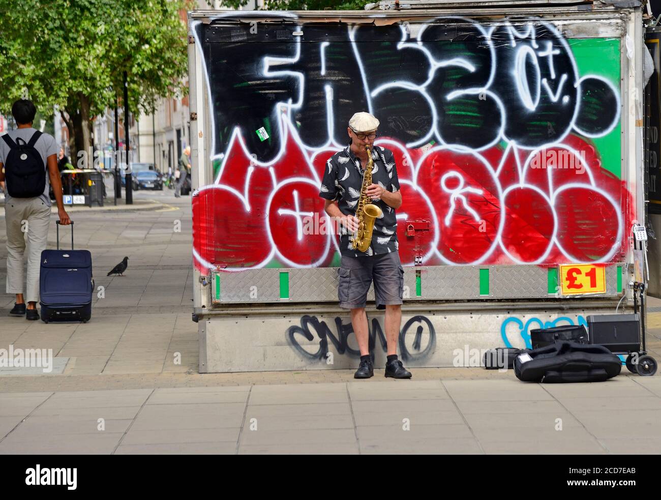 London, England, UK. Busker playing the saxophone in front of graffiti in Oxford Street Stock Photo
