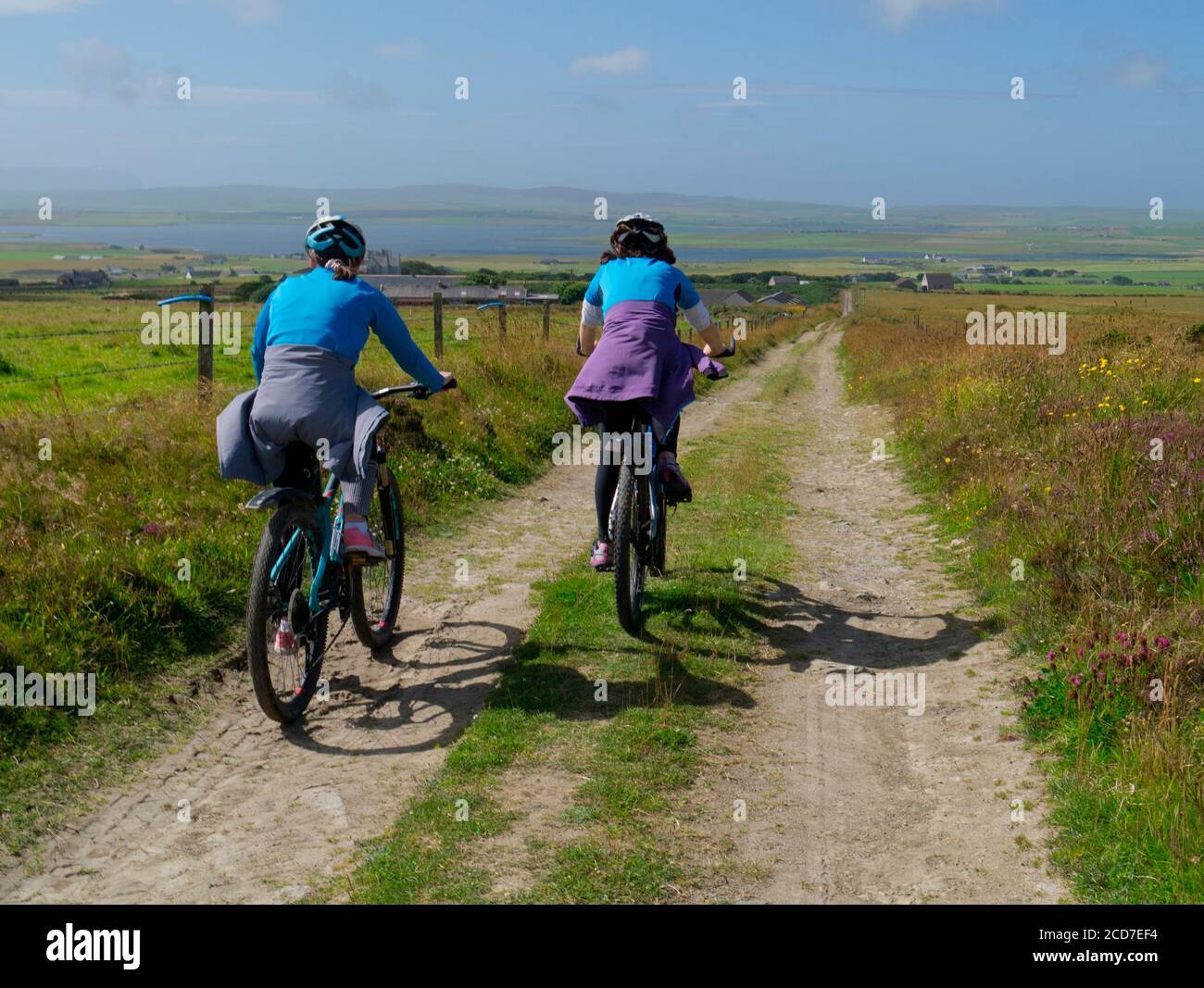 Mother and daughter cycling on farm track, Orkney Isles Stock Photo