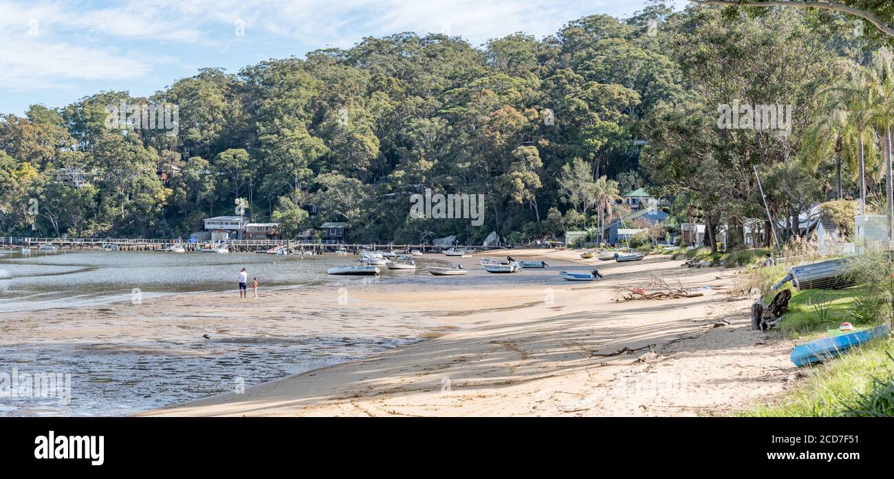 People walk and play on the sand at low tide at Bradleys Beach on Dangar Island in the Hawkesbury River 55kms north of Sydney, Australia Stock Photo