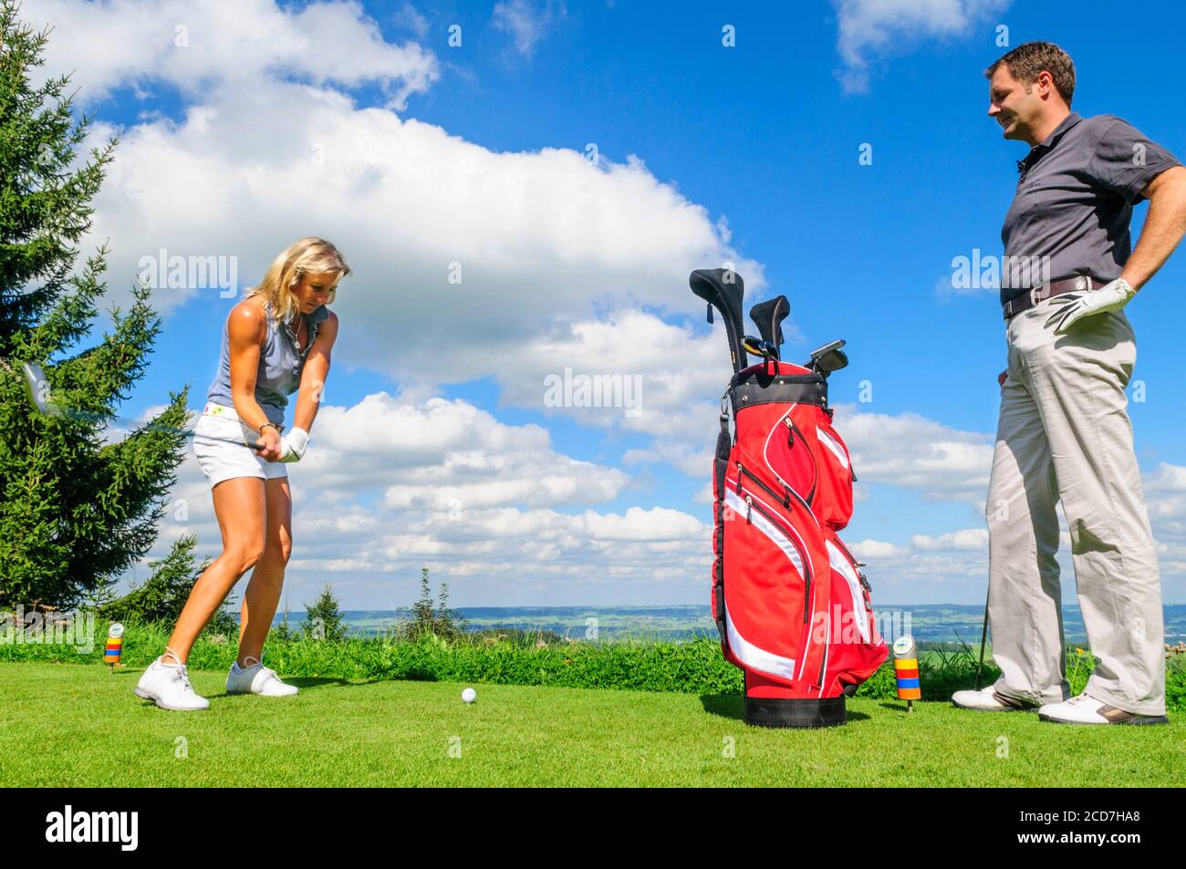 Man and woman playing golf on a beautiful parkland course at a sunny day in summertime Stock Photo