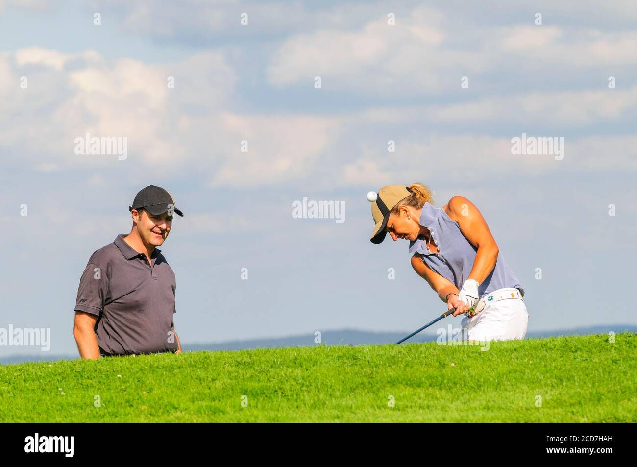Man and woman playing golf on a beautiful parkland course at a sunny day in summertime Stock Photo