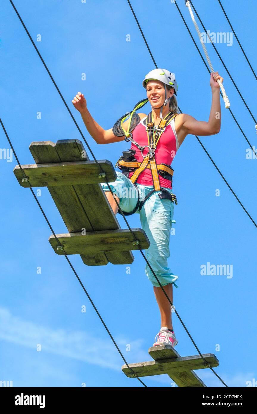 Young people doing exercises in high rope course at a sunny day Stock Photo