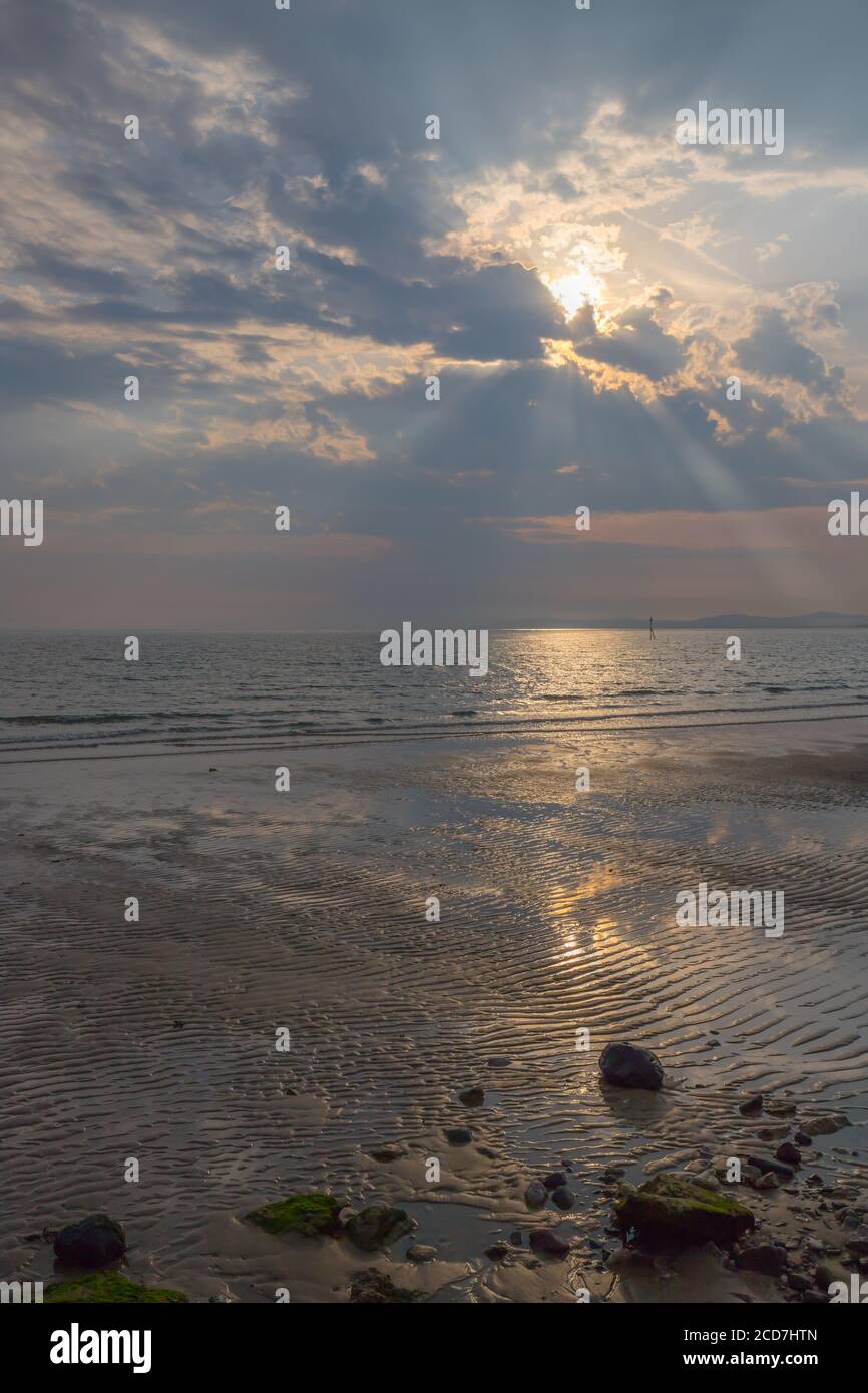 Dramatic sky with sun rays above Colwyn bay, North Wales. Dawn sunrise on the coast with a calm sea Stock Photo