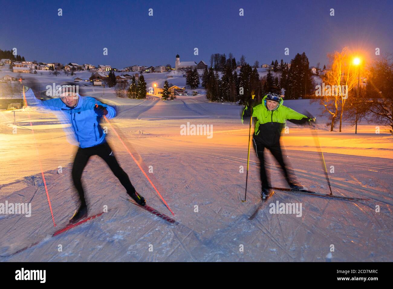 Two skiers doing a skating exercise on winter evening on floodlight slopes Stock Photo