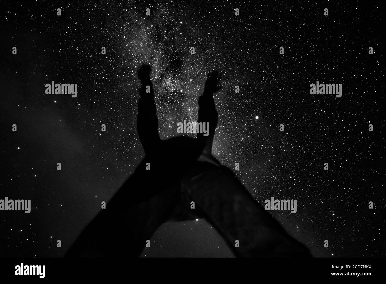 A man lifts his arms toward the Milky Way galaxy stars & astrophotography Cherry Springs night sky views solar system universe stargazing Stock Photo