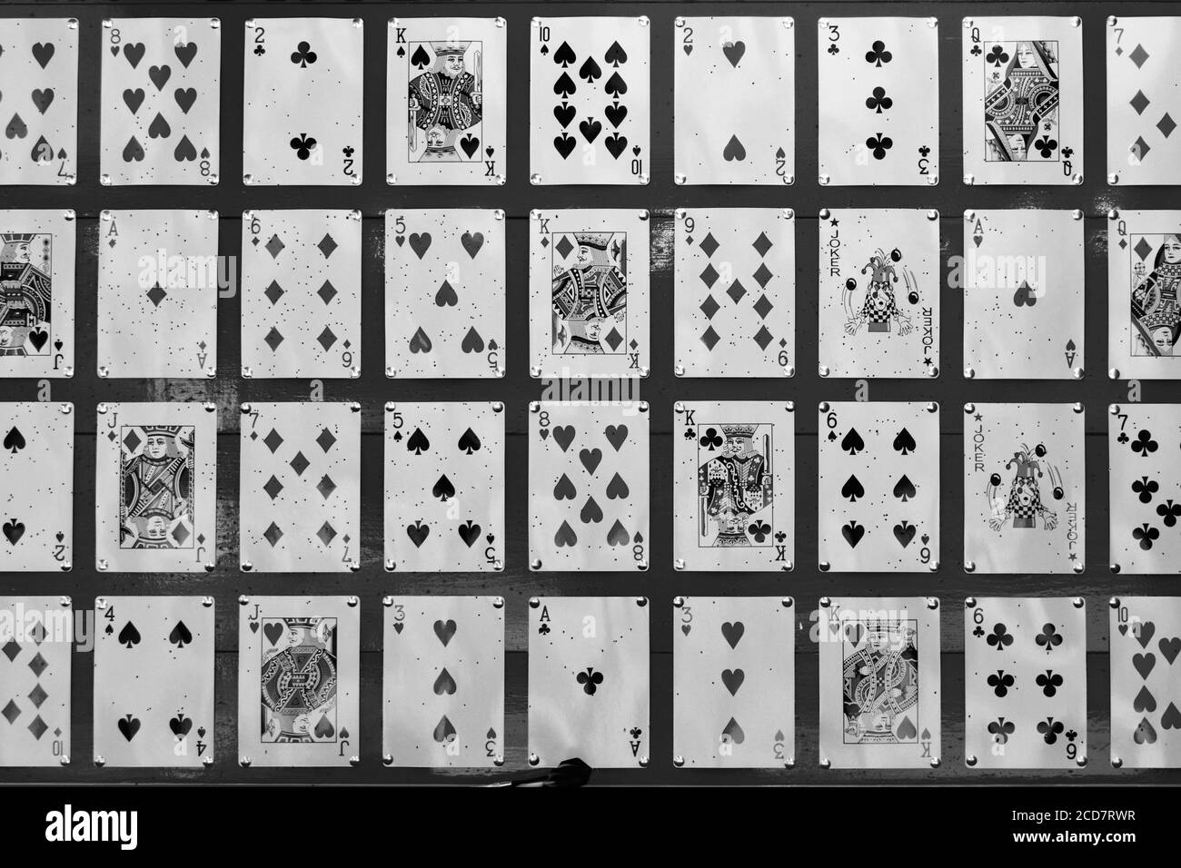 close up black and white image of playing cards pinned to a red board for a game using darts Stock Photo