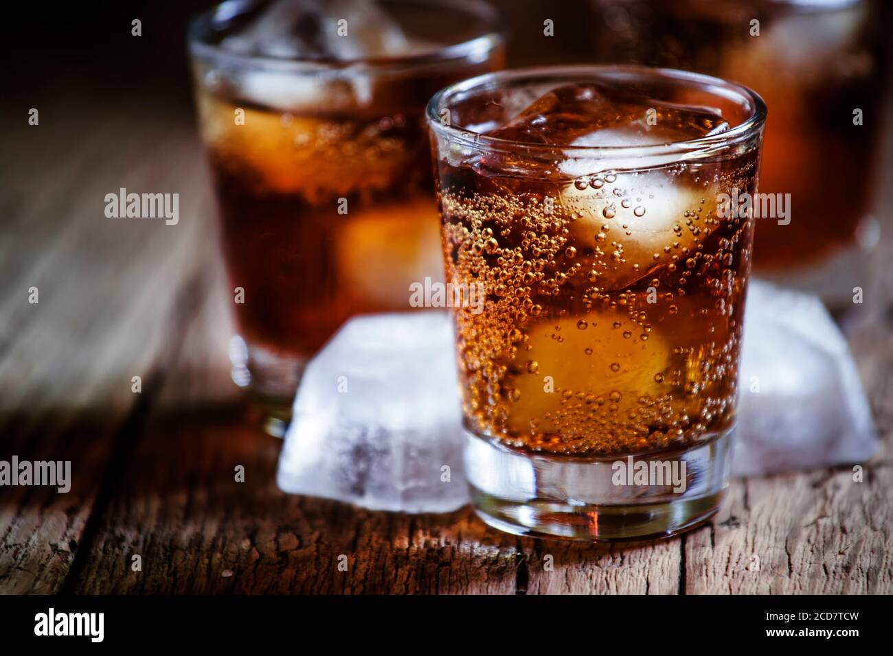 Alcoholic cocktail bourbon cola with whiskey and ice cubes, vintage wooden background, selective focus Stock Photo