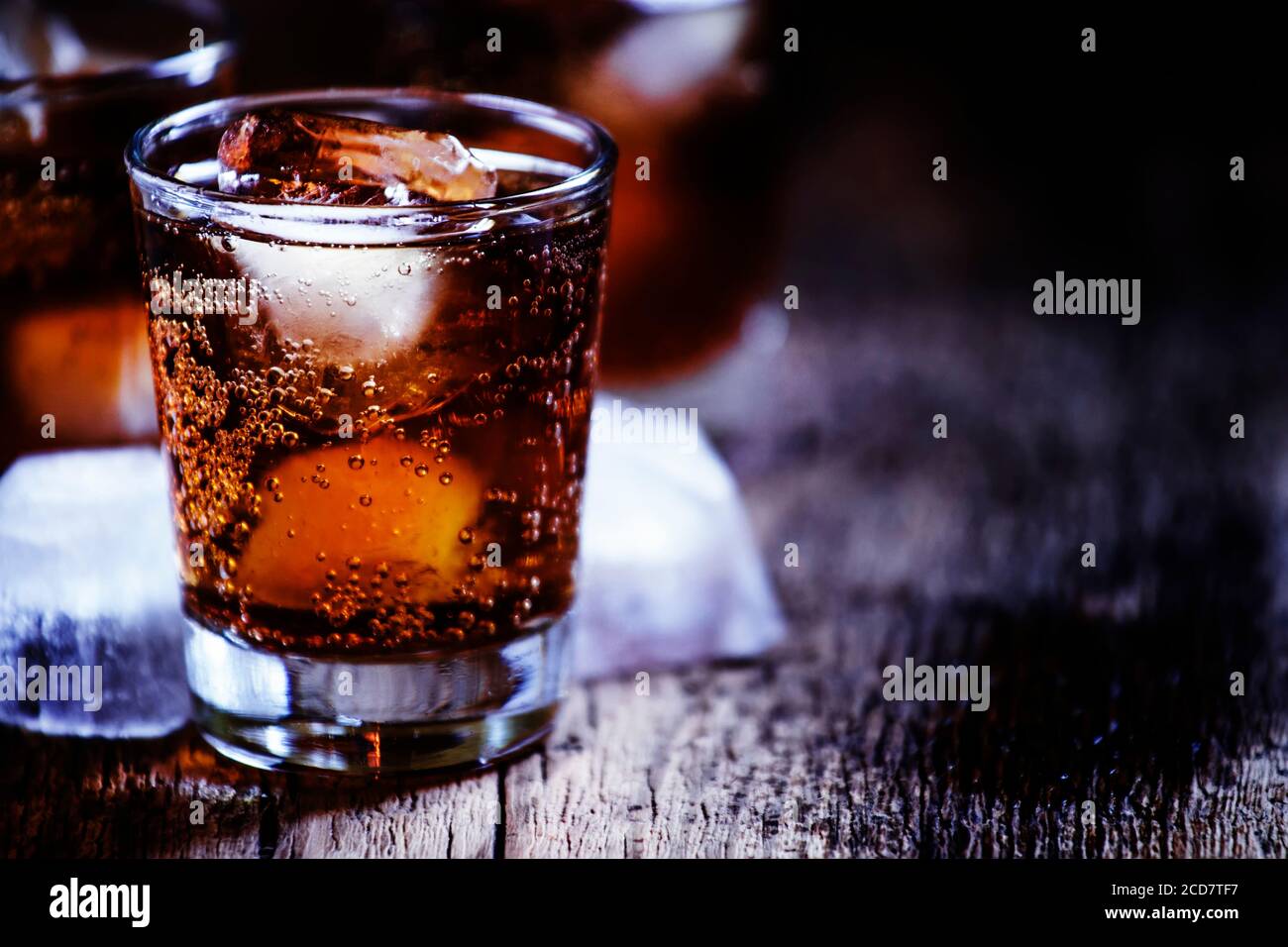 Alcoholic cocktail bourbon cola with whiskey and ice cubes, vintage wooden background, selective focus Stock Photo